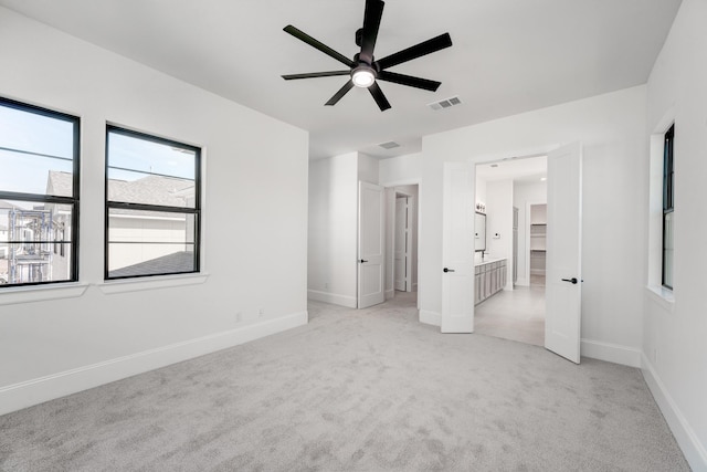 unfurnished bedroom featuring connected bathroom and light carpet