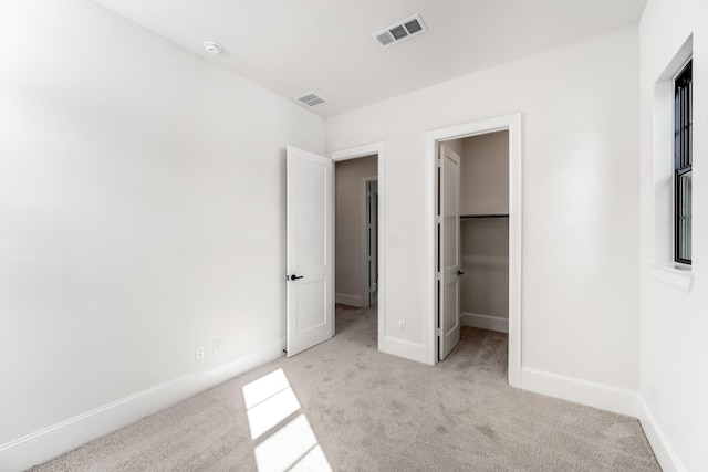 unfurnished bedroom featuring a spacious closet and light carpet