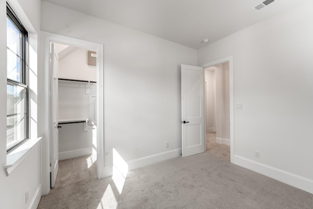 unfurnished bedroom with light carpet, a spacious closet, and a closet