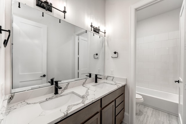 full bathroom featuring vanity, tiled shower / bath, and toilet