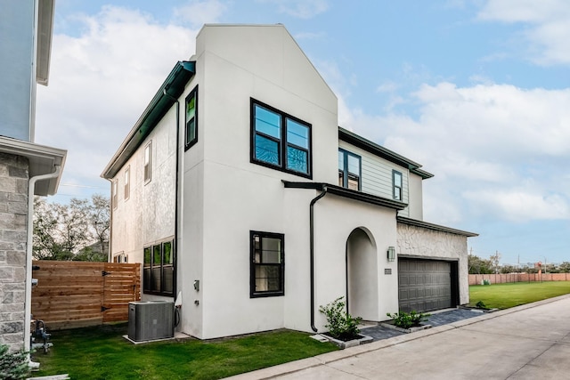 view of front of house with central AC unit, a garage, and a front lawn