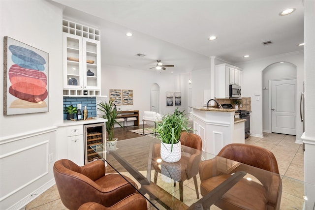 dining area with wine cooler, light tile patterned floors, crown molding, and ceiling fan