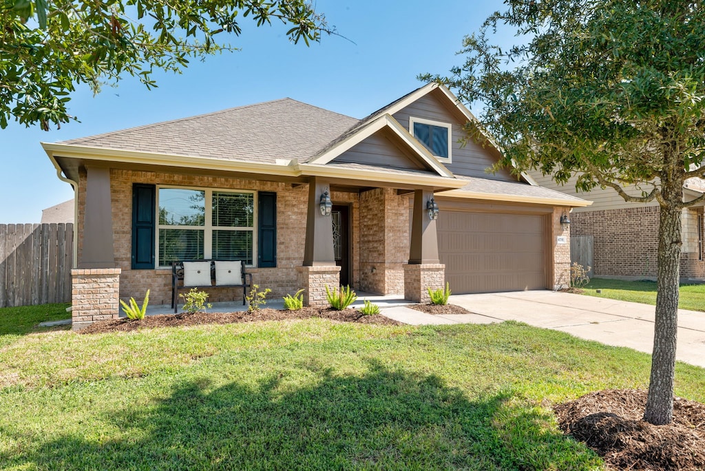 craftsman house with a garage, covered porch, and a front lawn