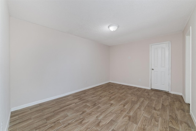 empty room with light hardwood / wood-style floors and a textured ceiling