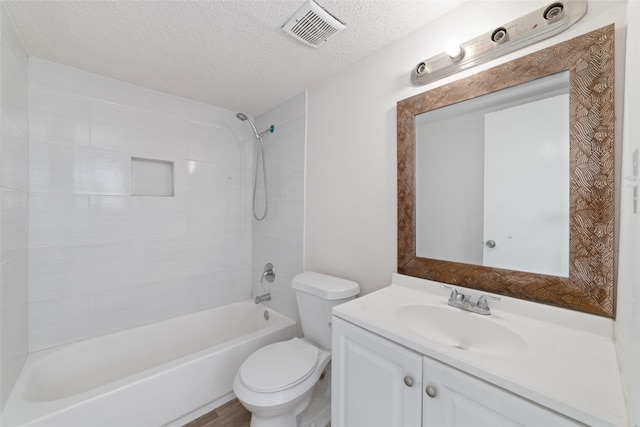 full bathroom featuring vanity, tiled shower / bath combo, toilet, and a textured ceiling