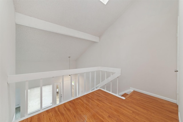 interior space with hardwood / wood-style floors and vaulted ceiling with beams