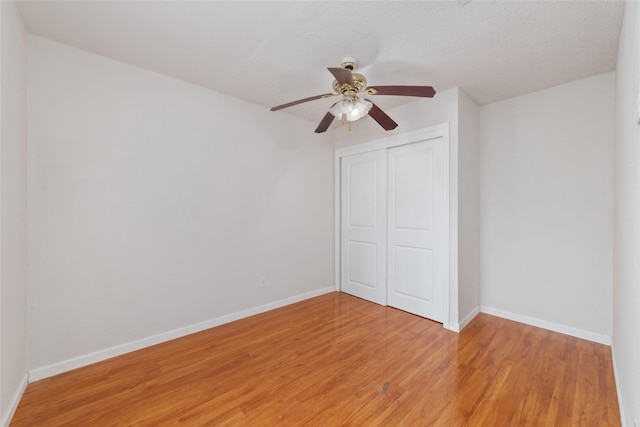 unfurnished bedroom with a closet, a textured ceiling, ceiling fan, and light hardwood / wood-style flooring