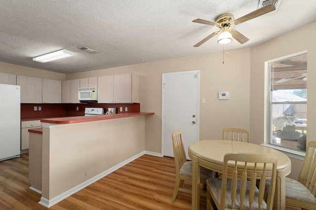 kitchen featuring hardwood / wood-style floors, white appliances, ceiling fan, kitchen peninsula, and a textured ceiling