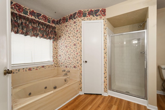 bathroom featuring toilet, wood-type flooring, plus walk in shower, and a textured ceiling