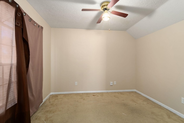 carpeted spare room featuring ceiling fan, vaulted ceiling, and a textured ceiling