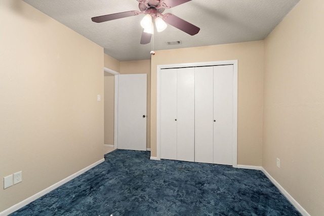 unfurnished bedroom featuring ceiling fan, a closet, dark carpet, and a textured ceiling