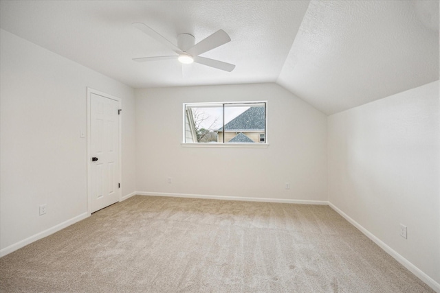 additional living space with vaulted ceiling, ceiling fan, light carpet, and a textured ceiling