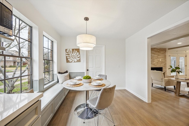 dining space with breakfast area, a large fireplace, and light hardwood / wood-style flooring