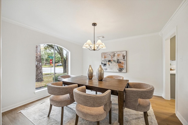 dining area with wood-type flooring, ornamental molding, and an inviting chandelier