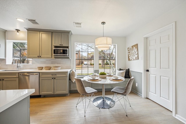 dining space with breakfast area, light hardwood / wood-style floors, sink, and a textured ceiling