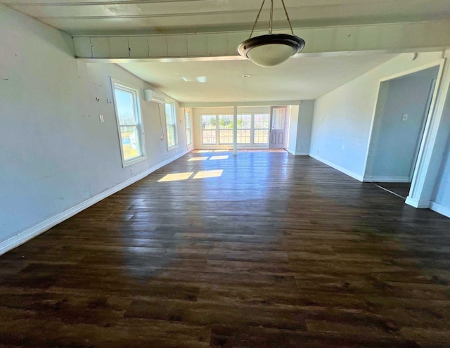 unfurnished room with plenty of natural light, a wall mounted AC, and dark hardwood / wood-style flooring