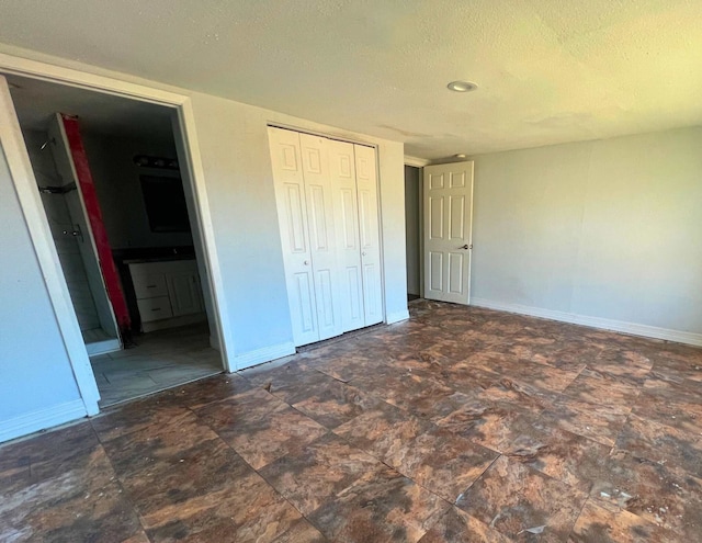 unfurnished bedroom featuring ensuite bath, a textured ceiling, and a closet