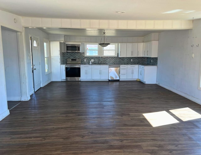 kitchen with sink, appliances with stainless steel finishes, white cabinetry, backsplash, and dark hardwood / wood-style flooring