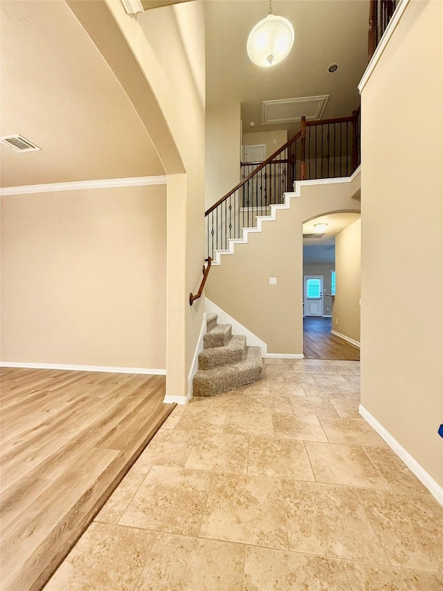 staircase with crown molding, hardwood / wood-style flooring, and a high ceiling