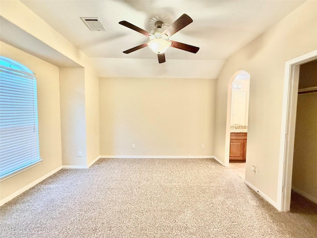 unfurnished bedroom with ceiling fan, light colored carpet, connected bathroom, and vaulted ceiling