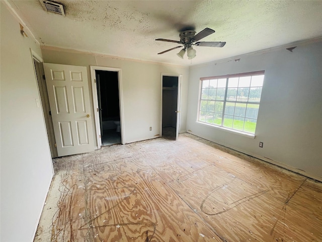 unfurnished bedroom featuring ceiling fan, crown molding, a textured ceiling, and ensuite bathroom