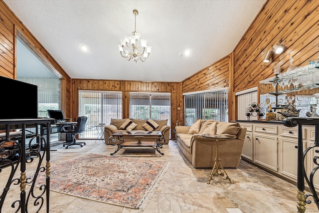 living room with a chandelier, high vaulted ceiling, a textured ceiling, and wood walls