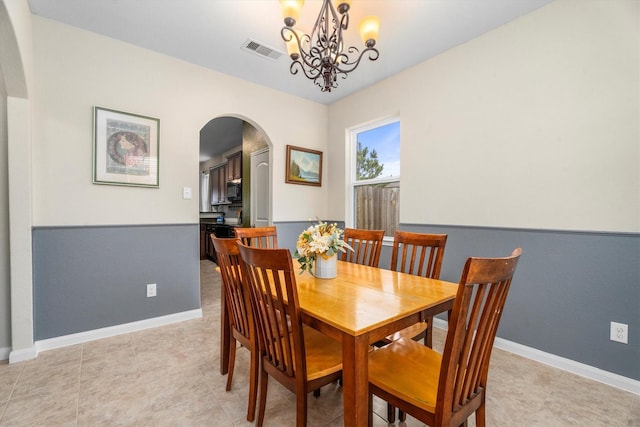 dining room featuring a chandelier, arched walkways, visible vents, and baseboards