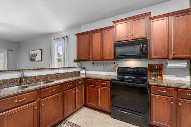 kitchen featuring light tile patterned floors, dark stone counters, sink, and black appliances