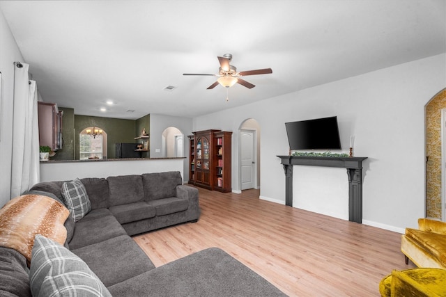 living room featuring ceiling fan with notable chandelier and wood-type flooring