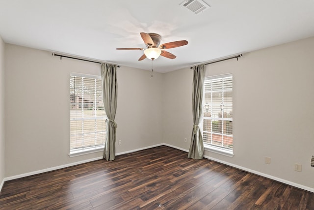 empty room featuring a wealth of natural light, dark hardwood / wood-style floors, and ceiling fan