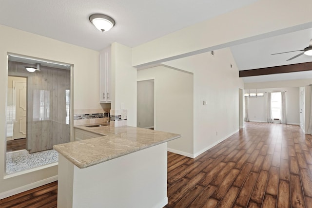 kitchen featuring dark wood-type flooring, kitchen peninsula, sink, and white cabinets