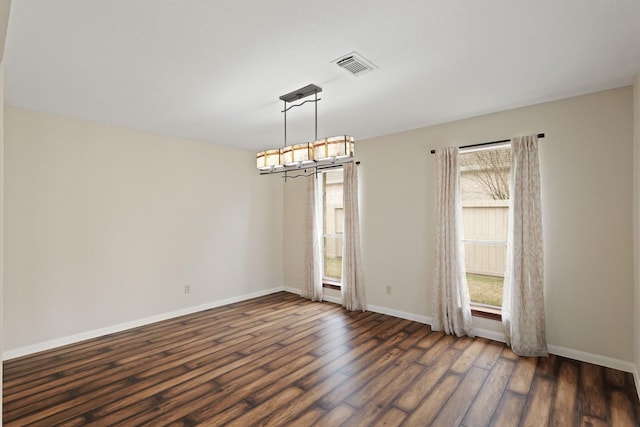 spare room featuring an inviting chandelier and dark hardwood / wood-style flooring