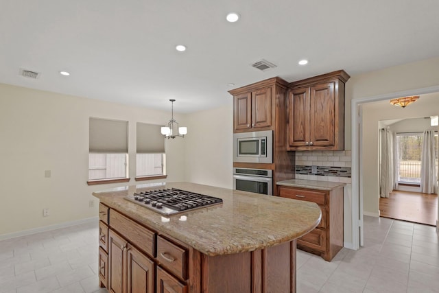 kitchen with light tile patterned floors, appliances with stainless steel finishes, decorative backsplash, decorative light fixtures, and a chandelier