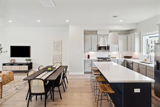 kitchen with gray cabinets, appliances with stainless steel finishes, sink, and decorative light fixtures