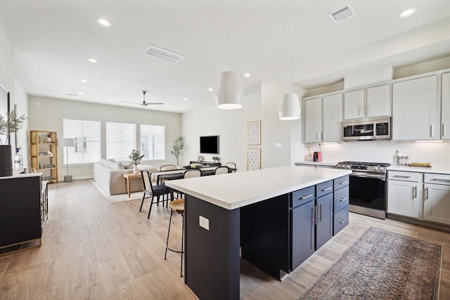 kitchen featuring appliances with stainless steel finishes, white cabinets, ceiling fan, and decorative light fixtures