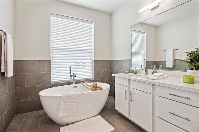 bathroom with tile walls, a bath, vanity, and tile patterned floors