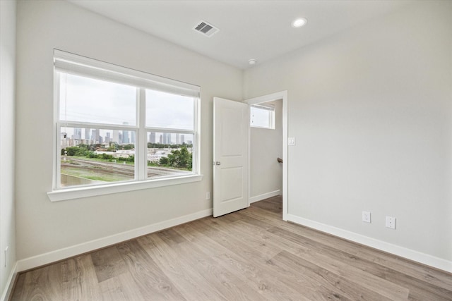 empty room with plenty of natural light and light hardwood / wood-style floors