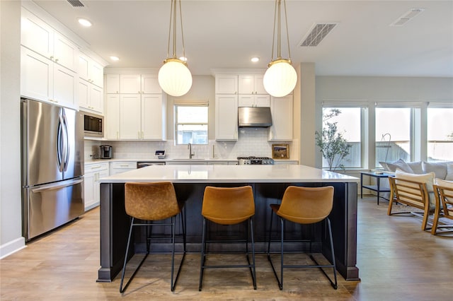 kitchen featuring pendant lighting, stainless steel fridge, white cabinetry, a center island, and built in microwave