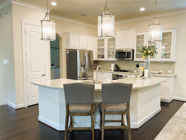 kitchen featuring stainless steel appliances, a kitchen island with sink, hanging light fixtures, and white cabinets