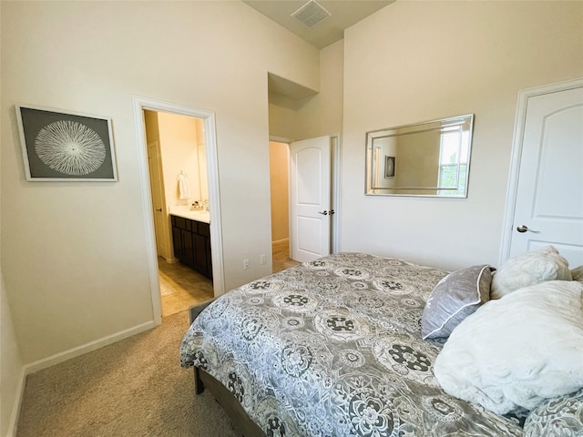 carpeted bedroom featuring ensuite bathroom and a high ceiling