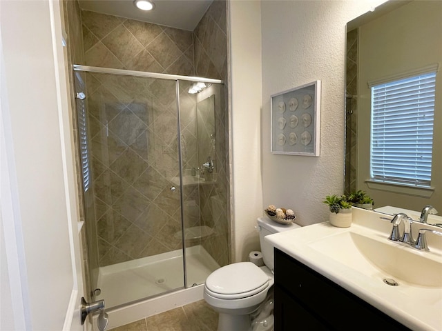 bathroom with vanity, a shower with shower door, tile patterned floors, and toilet