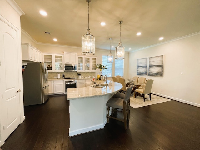 kitchen featuring pendant lighting, white cabinetry, sink, stainless steel appliances, and light stone countertops