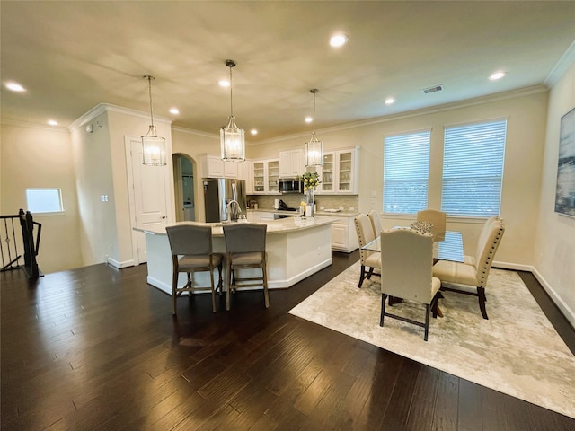 dining room with dark wood-type flooring, ornamental molding, and plenty of natural light