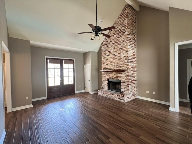 unfurnished living room featuring dark hardwood / wood-style floors, high vaulted ceiling, ceiling fan, a brick fireplace, and french doors