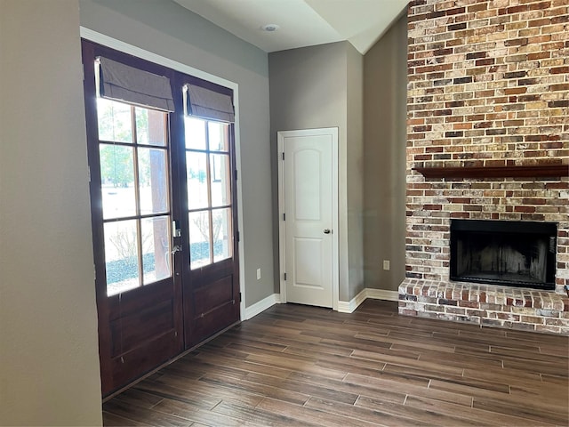 entrance foyer featuring lofted ceiling, dark hardwood / wood-style flooring, and a brick fireplace