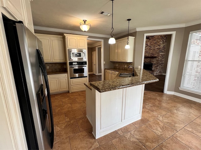 kitchen featuring ornamental molding, appliances with stainless steel finishes, kitchen peninsula, pendant lighting, and dark stone counters