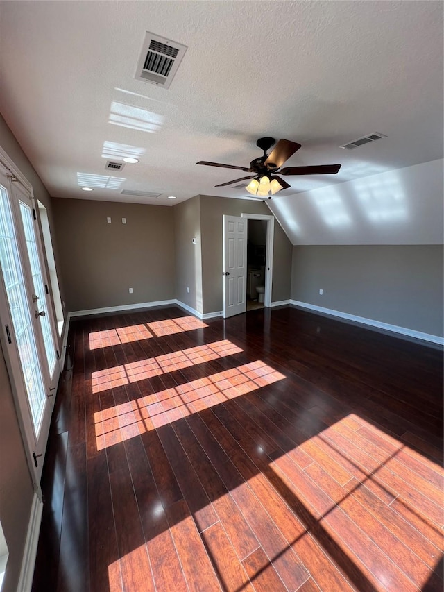 empty room featuring ceiling fan, dark hardwood / wood-style floors, a textured ceiling, vaulted ceiling, and french doors