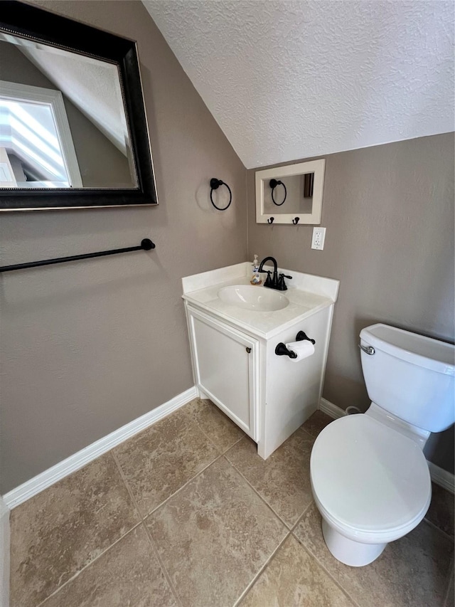 bathroom featuring vanity, a textured ceiling, vaulted ceiling, tile patterned floors, and toilet