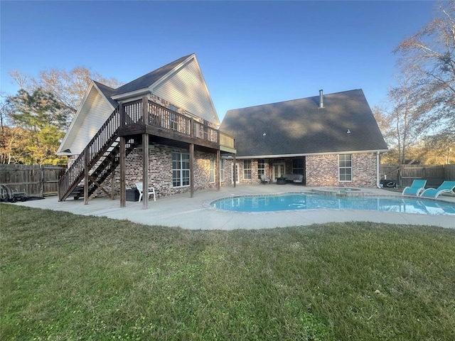 rear view of property featuring a pool side deck, a yard, and a patio