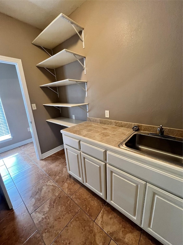 interior space featuring sink, tile countertops, white cabinets, and light tile patterned floors